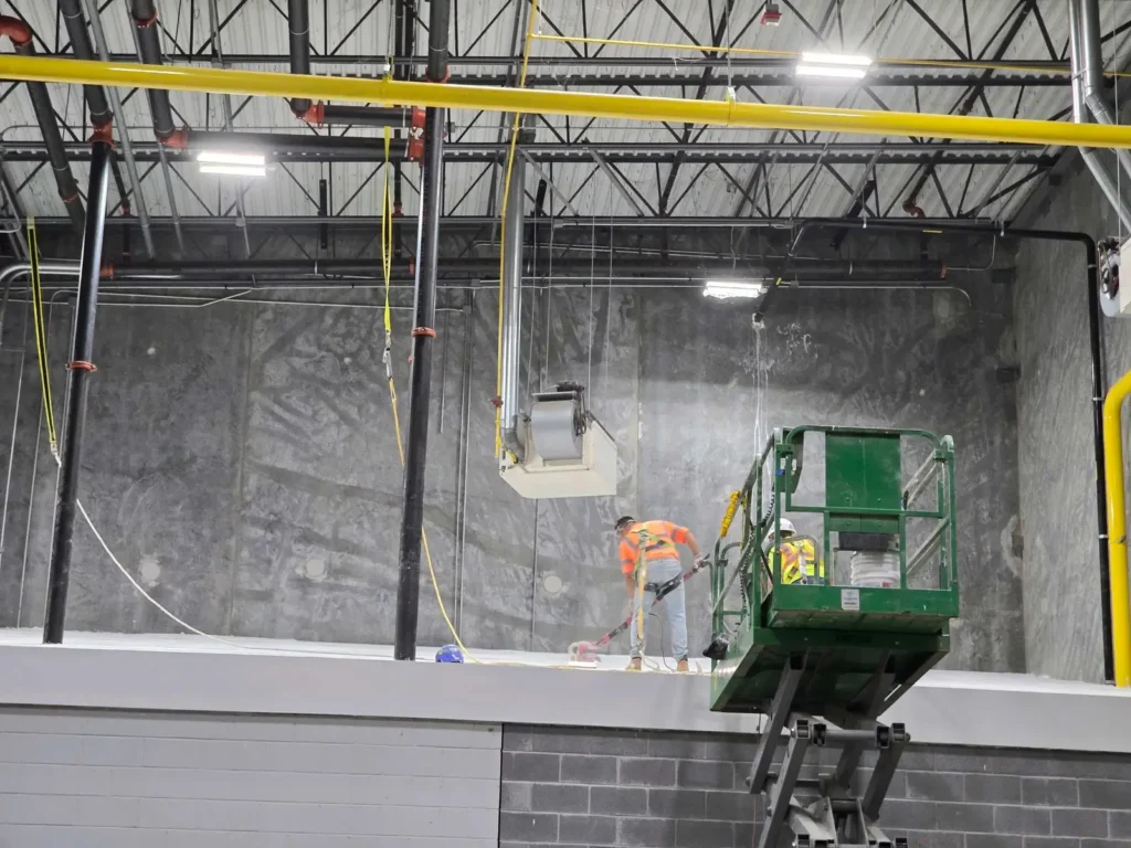 Manufacturing facility renovation in progress — crew finishing walls on a lift, Georgia